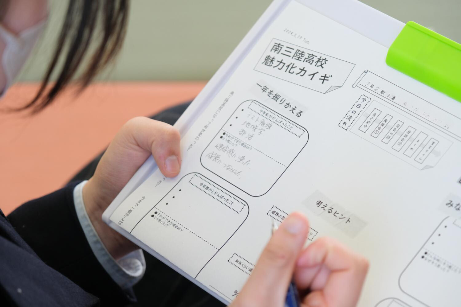 女子高生が「南三陸高校魅力化カイギ」と書かれた用紙にペンで記入している様子が写っている写真