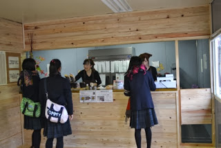 木目調のカウンター越しに店員と会話し注文している複数の女子学生の客の様子が写っている店内の写真