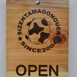 「SIZENTAMAGONOUEN SINCE 2004」と牛のロゴが焼き印のように刻まれ、「OPEN」と表示された木製の看板の写真