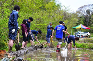 スコップを使い田んぼの土をきれいに整地している様子を写した写真