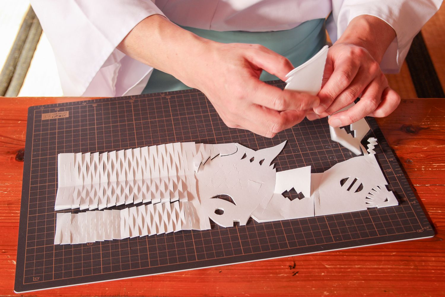 細かく切って作られた白い和紙を折り目に沿って少しずつ広げていく様子の写真