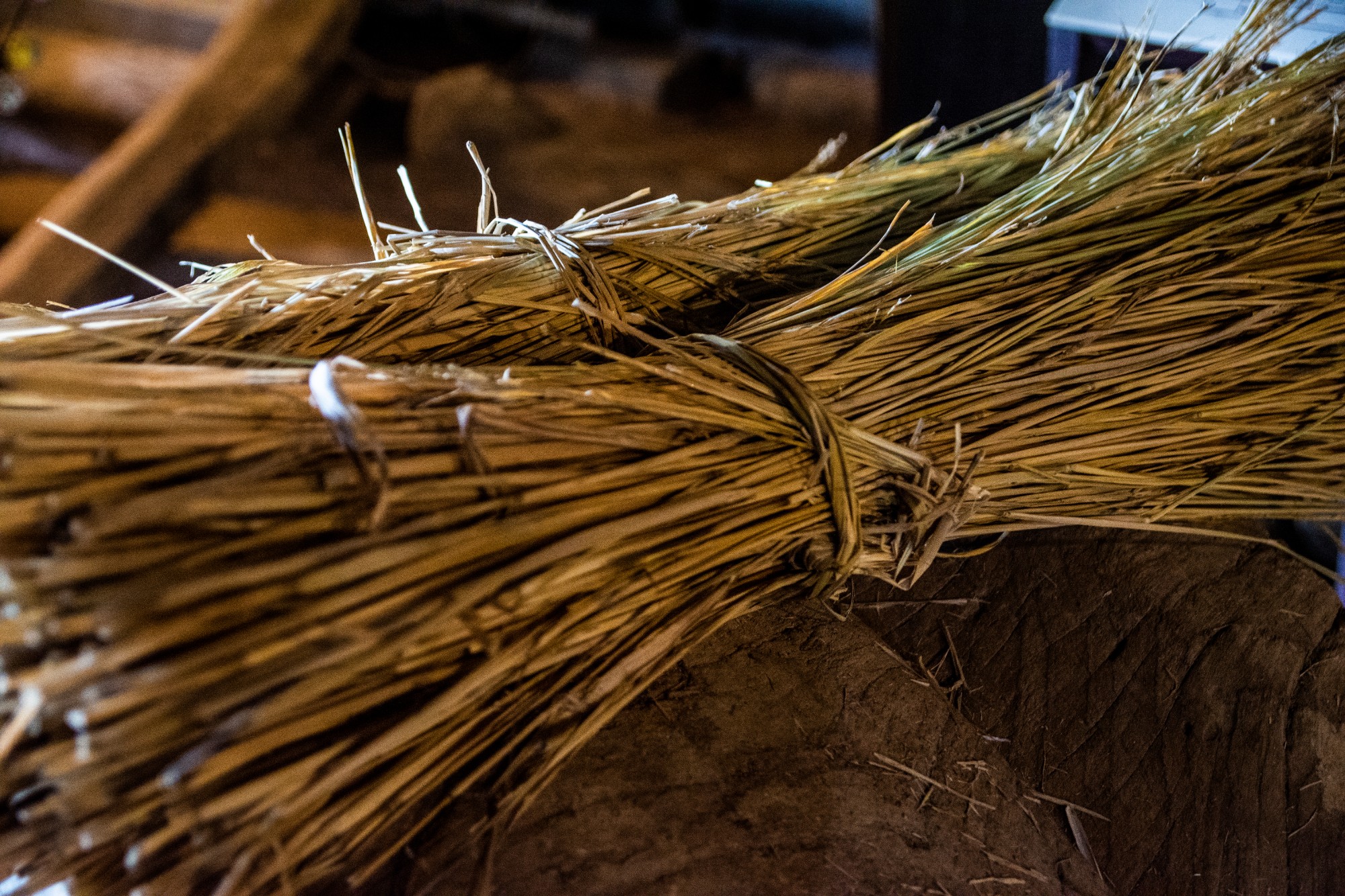 束ねられた藁が床の上に整然と置かれている写真