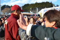 斎藤隆投手が優勝報告会の会場でファンに囲まれながら笑顔で交流し、ハイタッチを交わしている写真