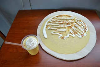 大きなクレープの上にクリームやキャラメルソースがかかっており、横にかぼちゃのスムージー入りのカップが置かれている写真