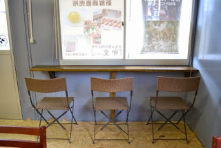 窓際のカウンターに並べられた3脚の椅子が置かれている店内の写真