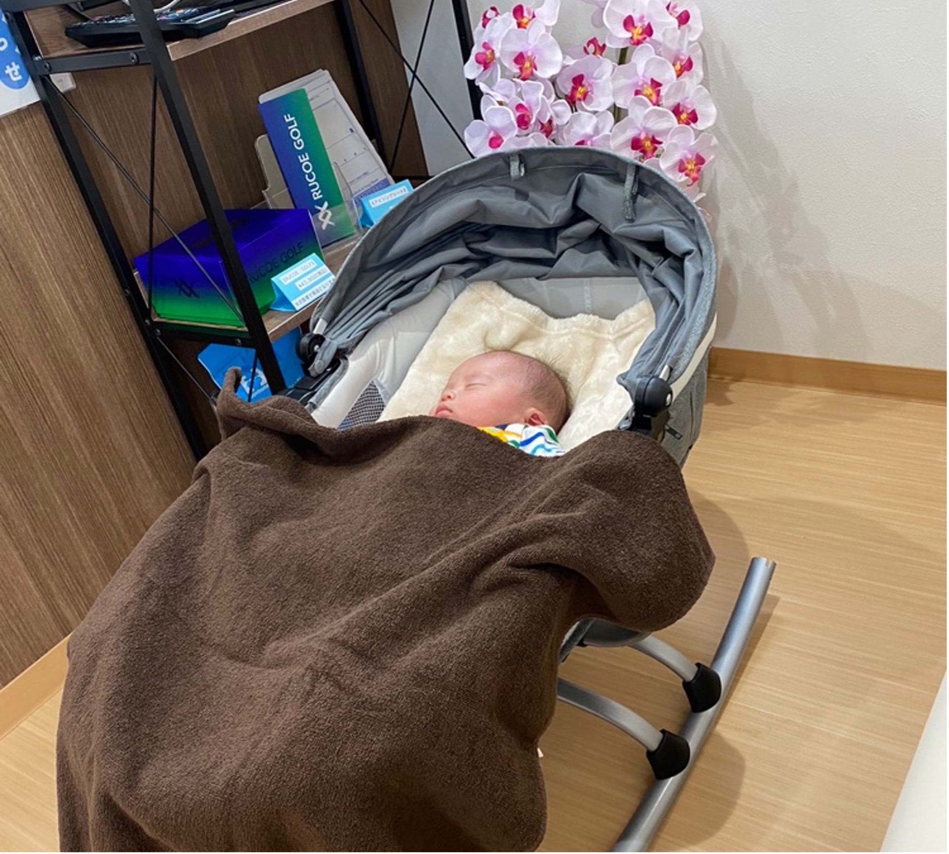 院内の一角にあるベビーベッドに赤ちゃんが毛布をかけて静かに眠っている写真