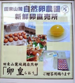 田束山麓自然卵農園の新鮮な卵直売所を紹介するポスターで、卵の黄身と鶏、卵の写真が掲載されている看板の写真
