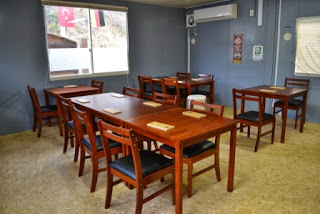 4人掛けや2人掛けの木製のテーブルが複数置かれた落ち着いた雰囲気の飲食スペースの写真