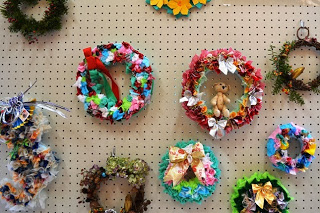 色とりどりの紙や飾りで作られた手作りのクリスマスリースが壁に飾られている写真