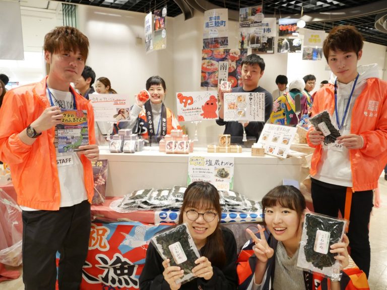 赤いジャンパーを着た大学生が海苔のパッケージを持っているブースの写真