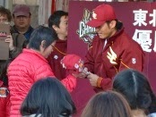 優勝報告会のステージ上で、牧田明久外野手が赤いジャンパーを着たファンに帽子を差し出され、丁寧にサインをしている写真