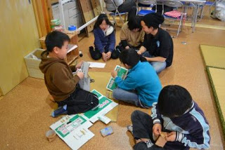 数人の子どもたちが段ボールや道具を使ってめんこ作りの工作に取り組んでいる様子を写した室内活動の写真