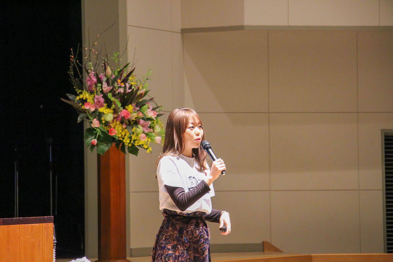 右手にマイクを持った小林さやかさんが新成人たちに講演をしている写真