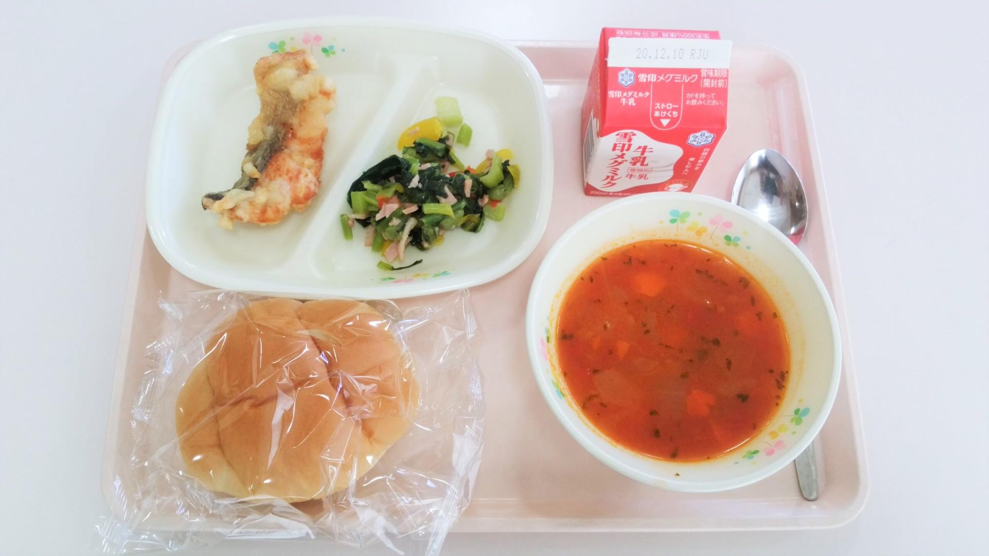 給食用のトレーに、鮭のポテト衣揚げ、野菜の和え物、タコのミネストローネ、パン、牛乳が乗っている学校給食の写真