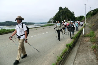 数人のハイカーが舗装された道路を歩いている様子を写した写真