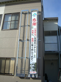 南三陸町役場の外壁の懸垂幕掲示スペースに「感謝 心温まるご支援ありがとう 元気に震災復興に取り組んでます」と書かれた大きな垂れ幕が掛かっている写真