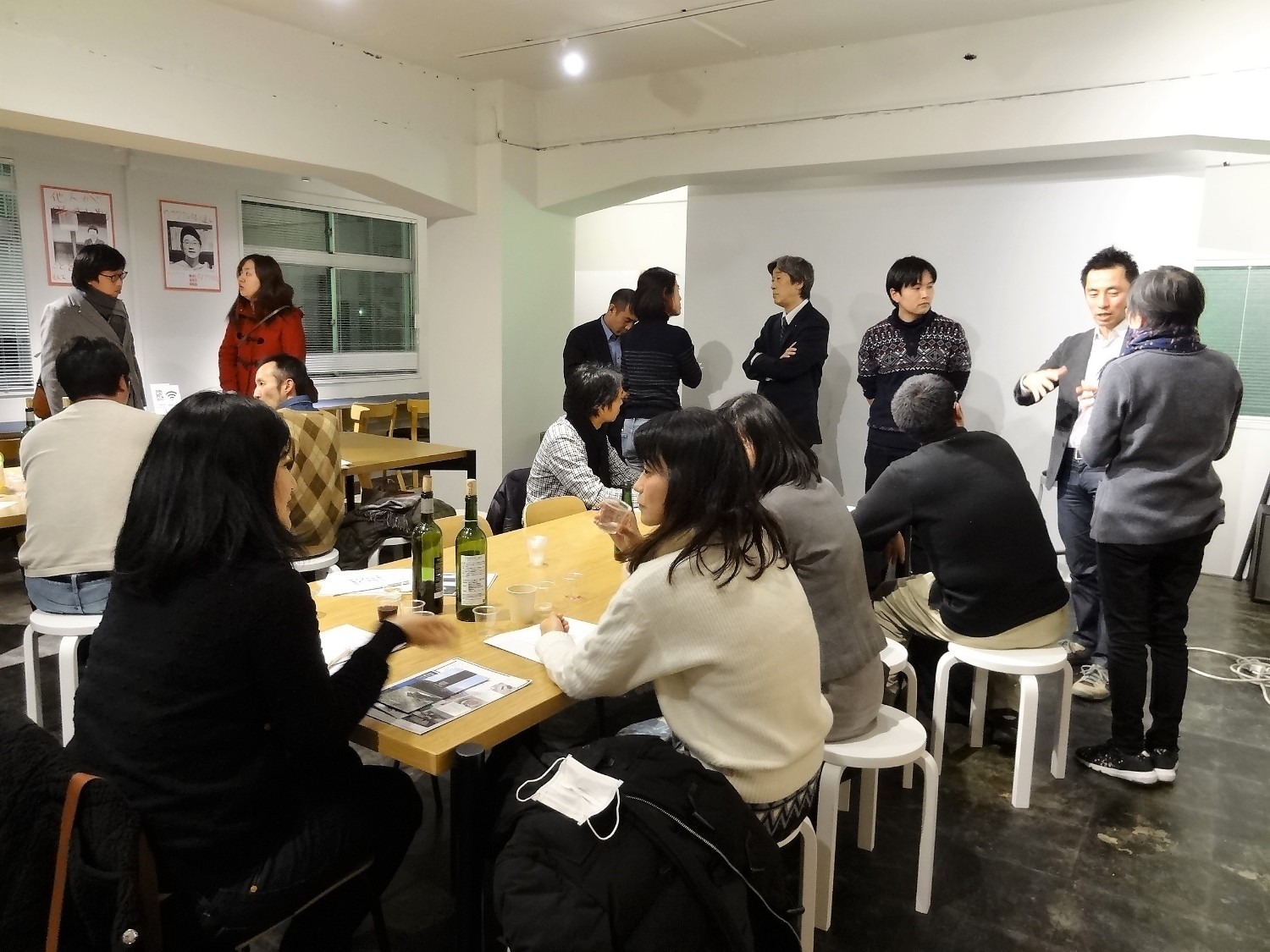 白い壁のある室内で、複数のグループが自由に立ち話や着席して交流している写真