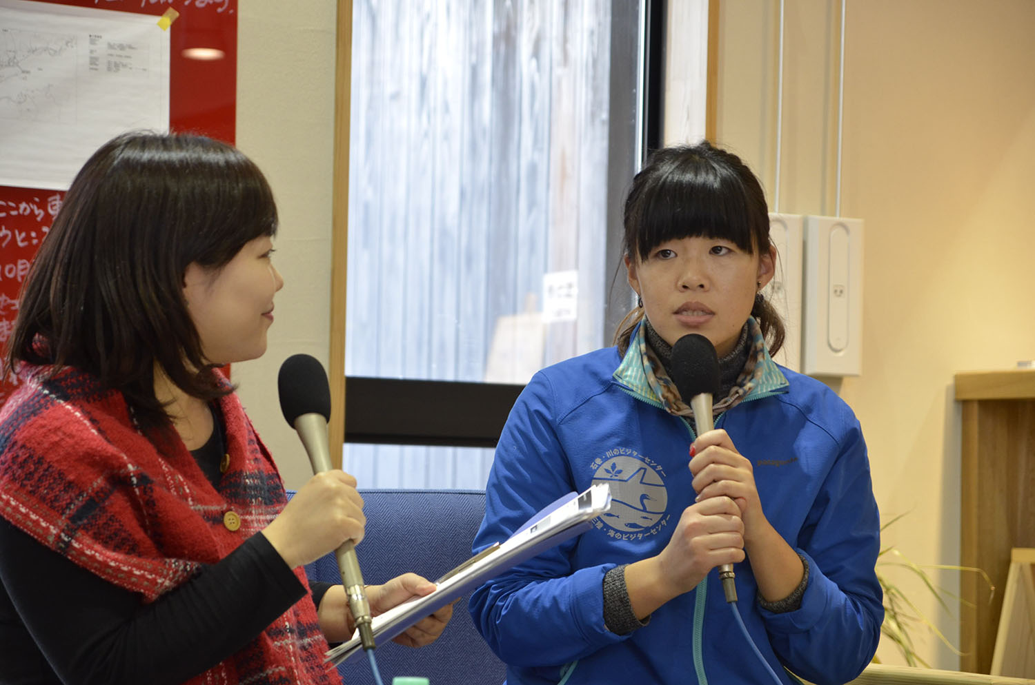 マイクを手にインタビューする女性リポーターと、真剣な表情でマイクを持って話している畠山さんの写真