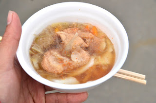 手に持った白い器の中に、鮭とにんじん、玉ねぎなどの野菜が入った温かい汁物が盛りつけられた写真