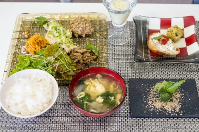 白いご飯と味噌汁、前菜、ドリンク、一皿にトウキの葉を使ったチキングリルやピり辛味噌、金平、サラダなどが丁寧に盛り付けられたトウキ尽くしの料理が並べられた料理全体の写真