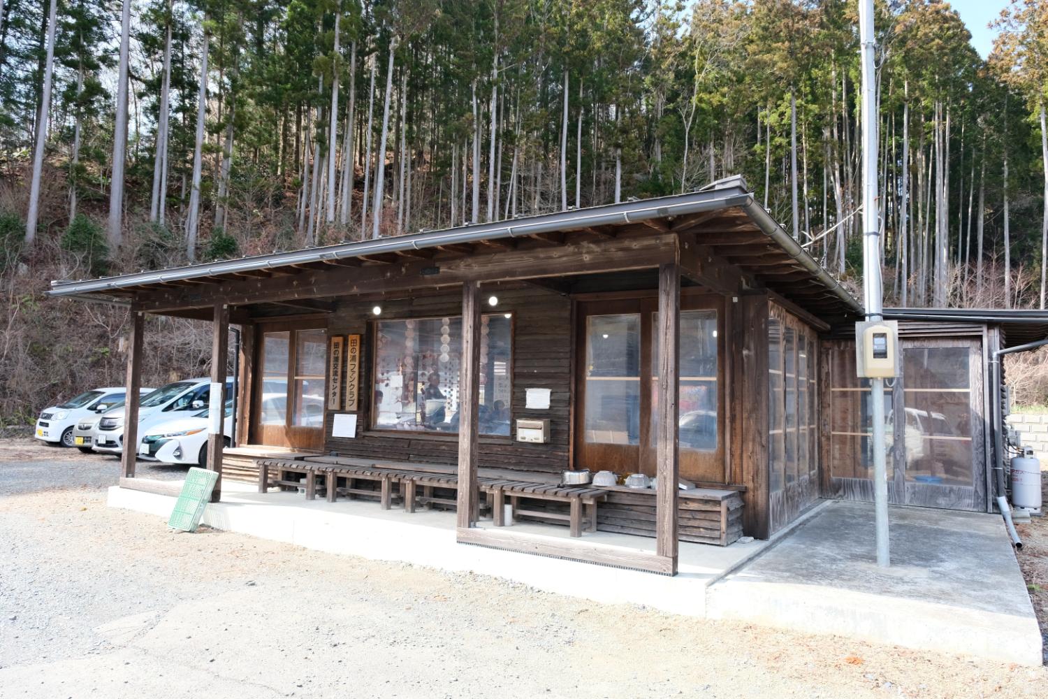 後ろには背の高い木々が密集して立っており、木造の事務所の写真