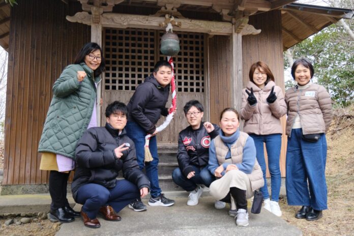 小さな神社の前で、7人の男女が笑顔で写っている主催者と高校生、企画課の皆さんとの集合