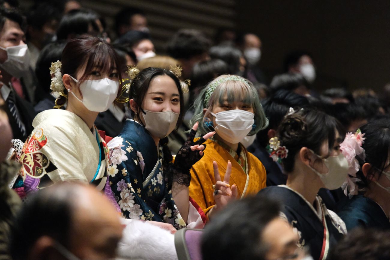 振袖姿の女性たちが笑顔でピースサインをしており、式典の合間のリラックスした雰囲気の様子の写真