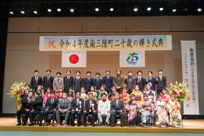 壇上に並んだ新成人たちと関係者が正面を向いて記念撮影している写真