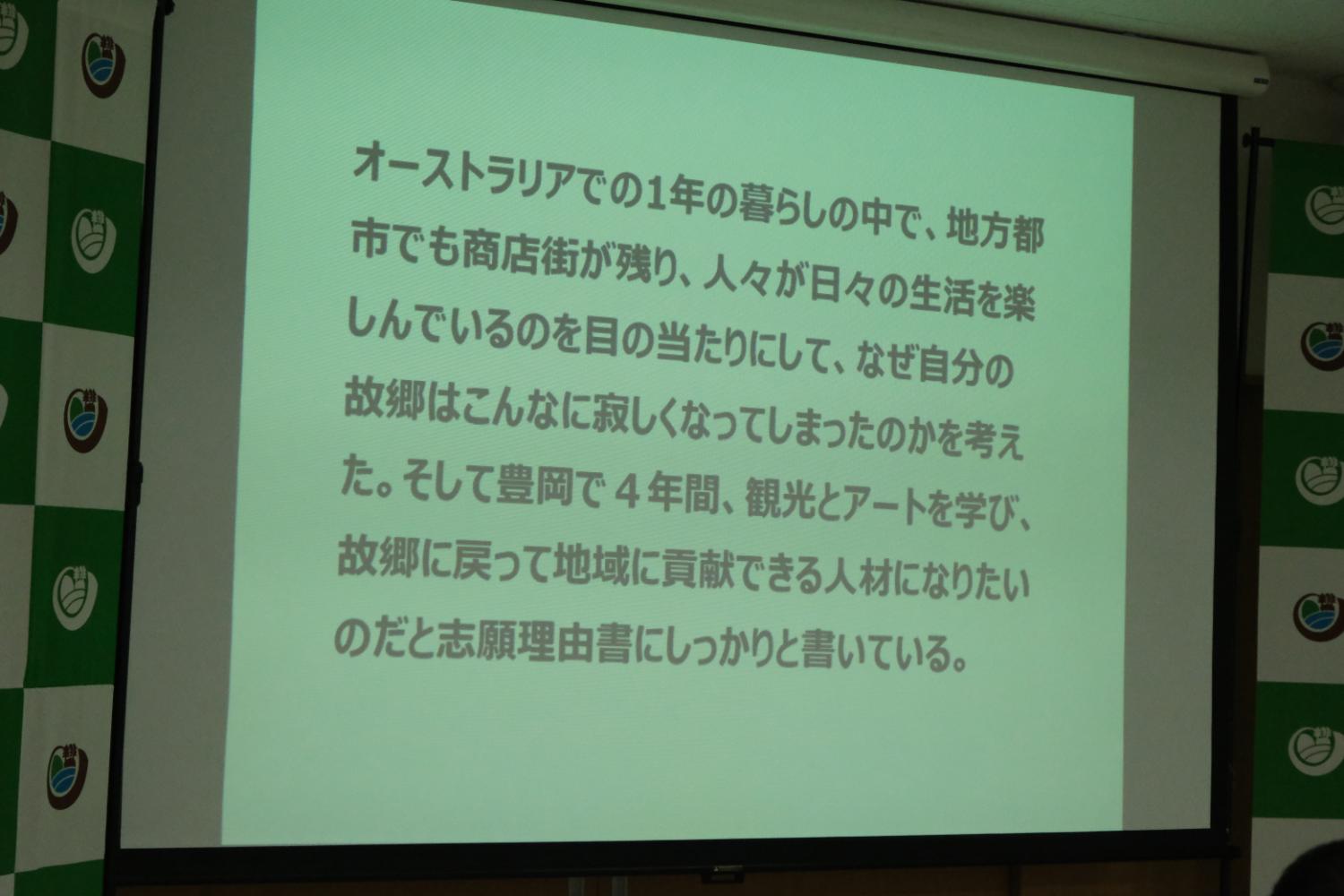 スクリーンにオーストラリアでの暮らしの中で経験したことを理由に、豊岡で4年間学び、故郷の地域に貢献できる人材になりたいと志願理由の文章が表示されている写真