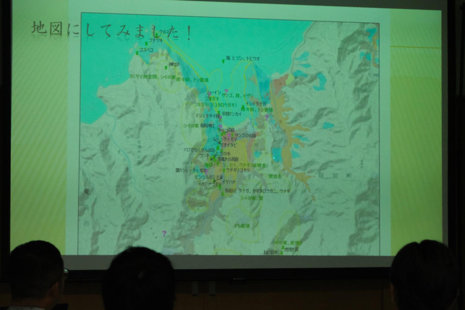 スクリーンに色とりどりの文字で様々な場所の名前が記されたケンムンの目撃情報が寄せられた地図が映し出されている写真