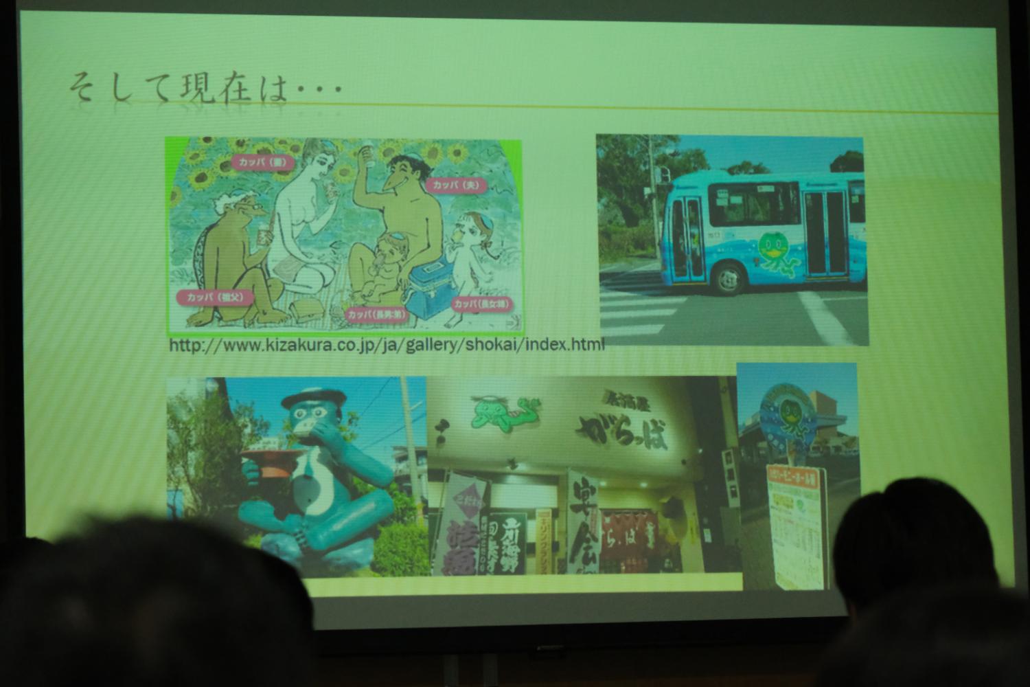 スクリーンに「そして現在は・・・」と題された文章と、カッパの絵やカッパが描かれたバス、カッパの像、カッパをテーマにした店の写真が映し出され、現在のカッパ文化について説明する写真