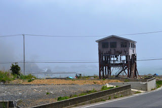 霧がかかった風景の広く開けた場所に、3階部分だけ残り、1.2階は柱だけ残っている建物が写っている写真
