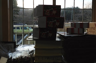 窓際に積み上げられたクリスマス柄の箱や荷物が逆光の中で見える写真