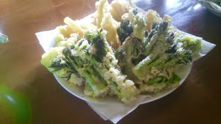 揚げたタラの芽とウドの天ぷらがクッキングシートを敷いた皿に盛られている写真