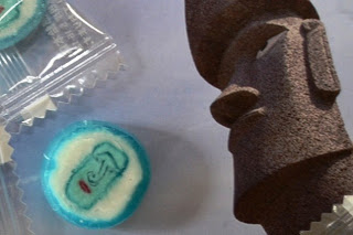 青と白の飴にモアイ像の顔が描かれており、その飴の隣にモアイ像の写真が置かれている写真