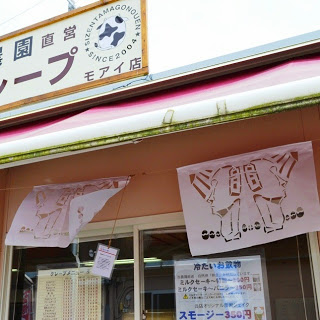 クレープ店の看板の下に、2体のモアイ像が描かれた切り絵が飾られている店舗の写真