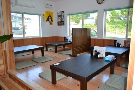 明るい木の床に低いテーブルが置かれ、座布団が敷かれた和風の座敷が広がり、大きな窓から外の風景が見える座敷席の写真