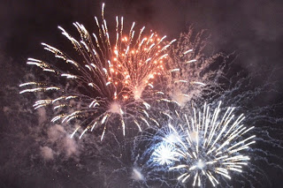 夜空いっぱいに赤と白の大きな花火が何発も重なって咲いている様子を真下から写した写真