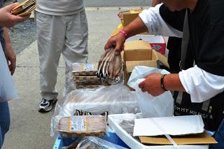 男性が干し魚のような水産加工品を取り出して袋にいれ、販売している様子の写真