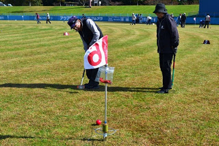 ホールに赤いボールが近づいている様子で、打った高齢男性と見守る別の参加者が写っている写真