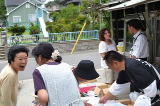 移動販売車の前で住民同士が笑顔で話しながら買い物をしており、楽しげな雰囲気が伝わる写真