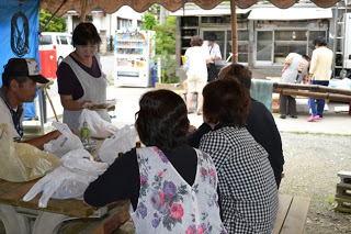 屋外のテーブルで住民同士が休憩し交流している様子の写真