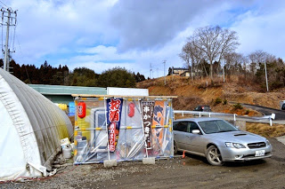 車の横にはたくさんの旗が並んでいるたてられたテントの前を写した写真
