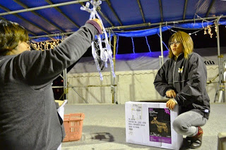 二人の女性が箱からトナカイ型のライト飾りを取り出しながら飾りつけの準備をしている写真