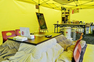 設置されたこたつとストーブがあり奥にカウンターがあるテント内の写真