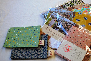 カラフルな模様のティッシュケースと、商品説明カードがついた透明な袋に入ったティッシュケースが机の上に並べられている写真