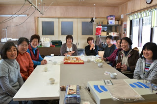 大きなテーブルを囲んで10名ほどの女性が笑顔で座り、お茶を飲みながら談笑している様子の写真