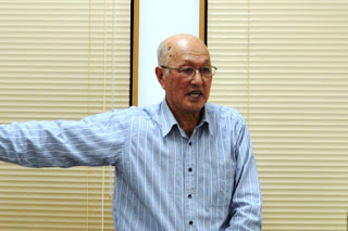 男澤達夫さんが左手を横に伸ばしながら話している写真