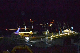 高台から見下ろした夜の仮設商店街がイルミネーションで彩られ、周囲に立ち並んだ旗が風に揺れている光景の写真