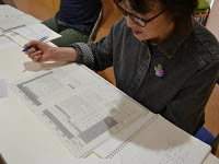 机に座ってペンを持ちながら広げた教材を見ている受講生の女性の写真